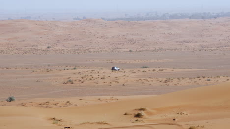 Land-Cruiser-4x4-Que-Viaja-A-Través-Del-Desierto-árido-Cerca-De-Roca-Fósil-En-Sharjah-Dubai,-Emiratos-árabes-Unidos