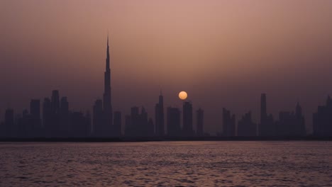 Full-Moon-Over-Dubai-Skyline-With-Dubai-Creek-At-Night-Dubai,-United-Arab-Emirates,-Middle-East
