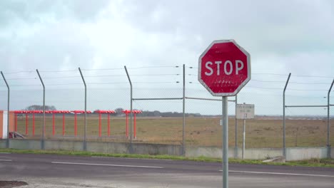 Stop-sign-on-the-road-next-to-an-empty-airport,-symbol-of-canceled-flights-and-holidays-during-Covid-19-pandemic