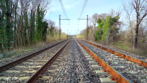 Walking-on-a-railroad-in-the-countryside-on-a-sunny-day,-beautiful-blue-sky-in-the-horizon,-point-of-view,-symbol-of-adventure