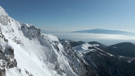 Erstaunliche-Luftaufnahme-Einer-Schneebedeckten-Bergklippe-An-Einem-Schönen-Sonnigen-Tag