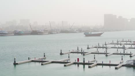 Puerto-Deportivo-Vacío-En-Dubai-Creek-Con-Barcos-De-Pesca-En-Segundo-Plano-En-Un-Día-De-Niebla-En-Dubai,-Emiratos-árabes-Unidos