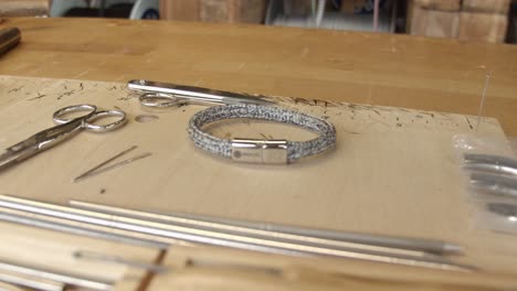 New-made-silver-color-bracelet-on-craftsman-table-with-tools-around