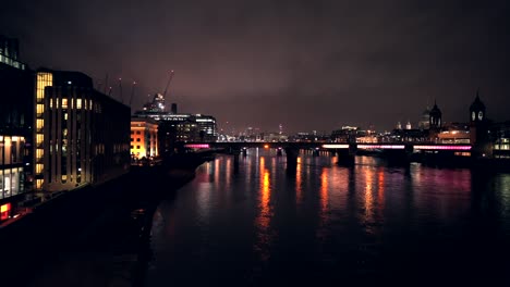 London-skyline-at-night,-view-of-the-city-buildings,-skyscrapers-from-London-Bridge,-beautiful-light-reflections-in-the-water-of-River-Thames