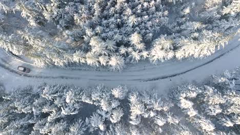 Aerial-view-over-a-car-moving-on-a-snowy-road-in-Switzerland