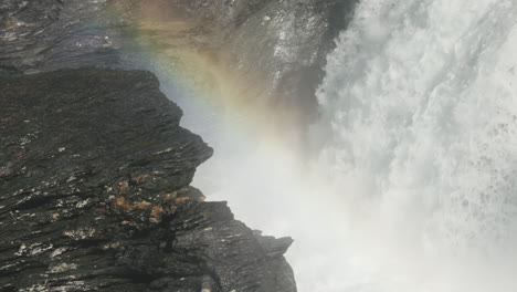 rainbow-formed-in-the-mist-of-powerful-Gaustafallet-waterfall-in-river-Gauste,-northern-Sweden