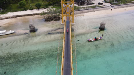 Aerial-View-Of-Bikers-Crossing-The-Yellow-Bridge-In-The-Klungkung-Regency-Off-The-East-Coast-Of-Bali,-Indonesia