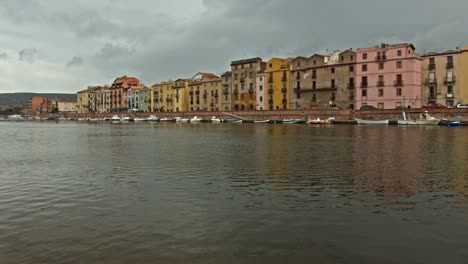 Majestic-village-of-Bosa-on-riverside-in-Sardinia-with-many-boats,-camera-panning-right-view