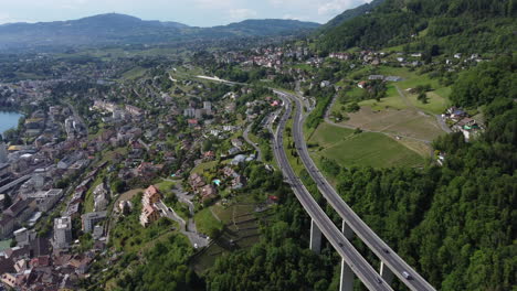 Expansive-aerial-view-high-above-a-motorway-in-Montreux,-Switzerland-on-a-sunny-day