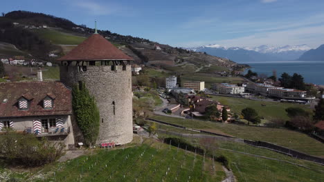Fast-orbit-shot-of-an-old-stone-winery-in-the-countryside-of-Lutry,-Switzerland-on-a-sunny-day