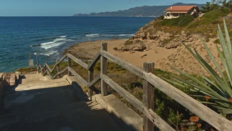 Old-wooden-handrail-leading-towards-majestic-coastline-beach-of-Sardinia