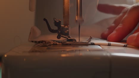 Side-view-of-needle-of-sewing-machine-in-slow-motion-with-hands-of-operator-visible