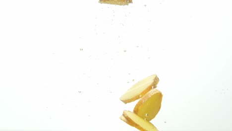 Pieces-of-ginger-floating-in-water-with-air-bubbles,-isolated-on-white-background
