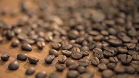 Fresh-coffee-beans-scattered-on-a-wooden-table-slow-motion