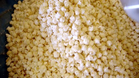 Pouring-golden-freshly-cooked-popcorns-into-huge-bowl,-handheld-view