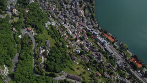 Expansive-aerial-top-down-and-tilt-up-shot-high-above-Montreux,-Swizerland-with-a-large-ferry-on-Lake-Geneva-and-Alps-in-the-background