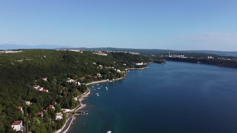 High-aerial-footage-over-ocean-waters-along-the-island-coast-of-Krk-Croatia-with-cities-and-industry-in-the-background
