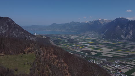Slow-expansive-aerial-shot-of-a-farmland-valley-in-Switzerland-on-a-sunny-day