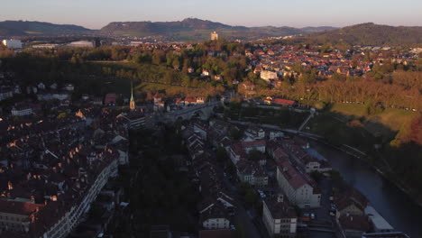 Langsame-Luftaufnahme-Hoch-über-Bern,-Schweiz,-Mit-Fahrzeugen,-Die-Bei-Sonnenuntergang-Eine-Große-Steinbrücke-überqueren