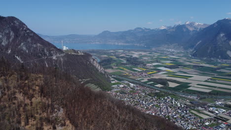 Slow-expansive-aerial-shot-of-a-farmland-valley-in-Switzerland-with-Lake-Geneva-in-the-background