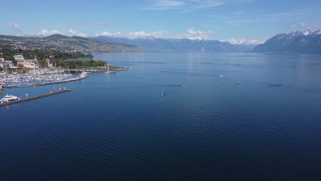 Slow-aerial-descent-shot-of-a-sail-boat-on-Lake-Geneva-in-Lausanne,-Switzerland-on-a-sunny-day
