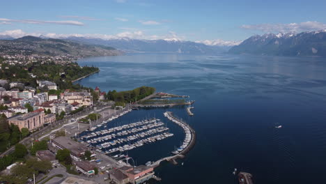 Expansive-aerial-shot-above-a-dock-in-Lausanne,-Switzerland-along-the-Lake-Geneva-waterfront-on-a-sunny-day