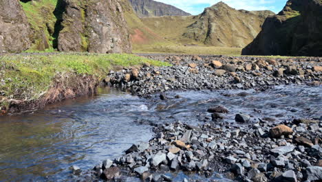 Mountain-stream-flowing-on-black-pebbles-in-the-valley-in-Iceland