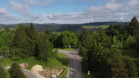 Slow-aerial-shot-of-a-road-and-forest-near-Sainte-Croix,-Switzerland-on-a-sunny-day