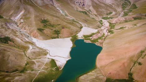 Aerial-View-Of-Lake-with-Calm-Blue-Waters-On-Foothill-Of-Mountains-In-Uzbekistan