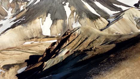 Las-Montañas-Doradas-Revelan-Un-Amplio-Valle-Y-Una-Diminuta-Silueta-De-Un-Excursionista-Caminando-En-Un-Desfiladero-Junto-Al-Río-En-Las-Montañas-Arcoiris-De-Landmannalaugar-En-Islandia