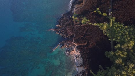 Aerial-view-of-where-the-blue-ocean-meets-the-blackened-shoreline