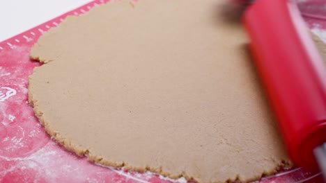 Flattening-gingerbread-dough-with-red-rolling-pin.-Closeup
