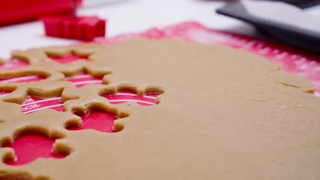 Woman-cutting-raw-gingerbread-dough-with-red-cutting-form