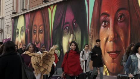 Turistas-Y-Transeúntes-En-Gran-Vía,-Callao,-Centro-De-La-Ciudad-De-Madrid-Con-Grafitti-Que-Representan-Mujeres-Anónimas