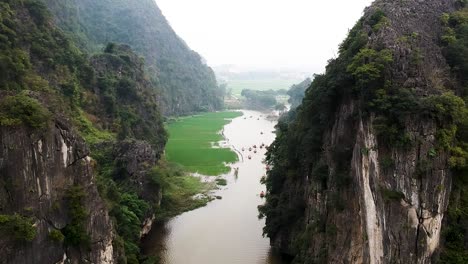 Aerial-shot-of-busy-river-boats-between-limestone-karsts-Trang-Ang,-Tam-Coc,-Ninh-Binh,-Vietnam