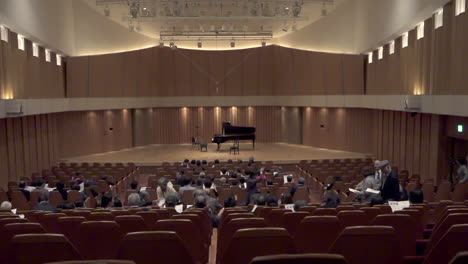 -Japanese-spectators-entrance-and-sitting-at-a-concert-hall-with-a-program-in-their-hands