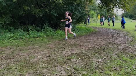 Girl-slips-and-falls-on-her-knees-while-running-cross-country-on-wet-and-muddy-trail-in-forest