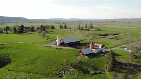 Aerial-push-in-shot-on-farm-toward-multiple-barns-during-summer-in-west-virginia