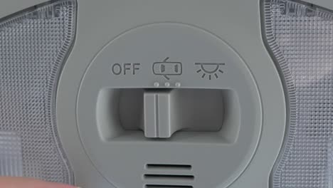 Eine-Weiße-Kaukasische-Hand,-Die-Den-Schalter-Eines-Deckenlichts-In-Einem-Neuen-Auto-Umlegt