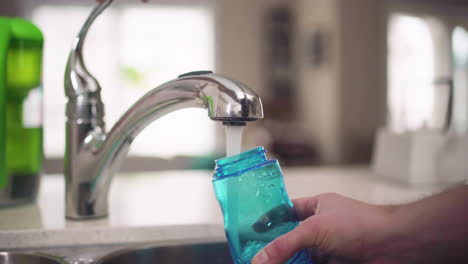 Hand-filling-up-a-water-bottle-from-a-kitchen-tap