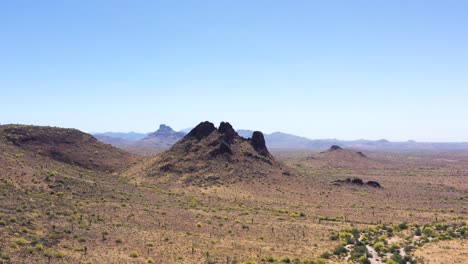 Aerial-pan-from-rugged-volcanic-rock-mountains-and-butte-to-open-desert-on-the-Salt-River-Pima-Indian-Reservation,-Scottsdale,-Arizona-Concept:-Sonoran-Desert,-rock-formations,-mountains