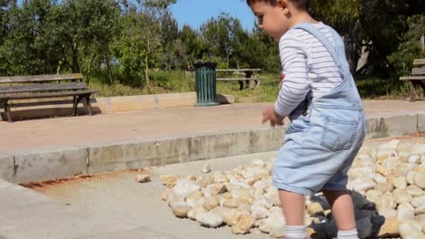Süßer-Zweijähriger-Junge,-Der-Im-Park-Mit-Steinen-Spielt