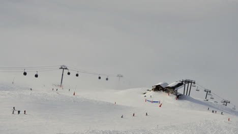 Lapso-De-Tiempo-De-Remontes-Y-Esquiadores-En-Meribel-En-Los-Alpes-Franceses,-Con-Nubes-Debajo-De-Los-Remontes