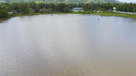 Aerial-view-across-group-of-men-adjusting-nets-in-tropical-lagoon-water