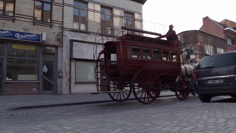 Two-large-horse-drawn-covered-wagons-pass-through-a-city-street