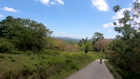 A-flowing-following-shot-of-a-motorcycle-riding-through-the-beautiful-lush-green-tropical-mountains-of-Bohol,-Philippines