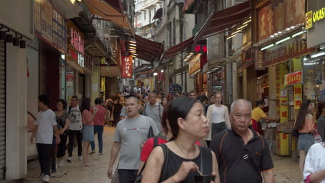 Tourists-walking-in-the-narrow-historical-street-of-Macau-with-numerous-street-shops-and-shop-signs,-Macau-SAR,-China