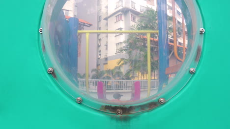 Behind-dirty-plastic-bubble-boy-slides-down-in-playground-area-fun-and-joy