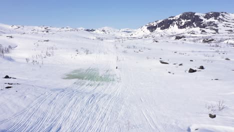 Aerial-view-of-person-on-snowmobile-in-snowy-mountain-landscape