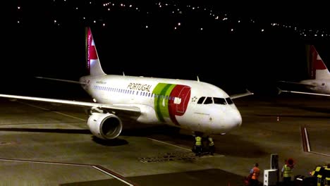 A-couple-of-airline-ramp-agents-secure-the-commercial-aircraft-fuselage-landing-gear-after-landing-the-aeroplane-from-a-late-night-flight